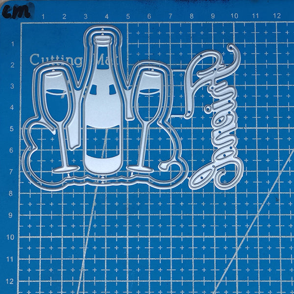 Metal die cutters with bottle, glasses, and 'Happy New Year' text on a blue cutting mat.