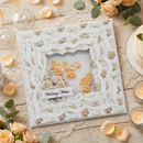 Decorative wedding card with floral design on a wooden table with flowers and candles.