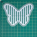 Butterfly-shaped cutting die on a green grid background