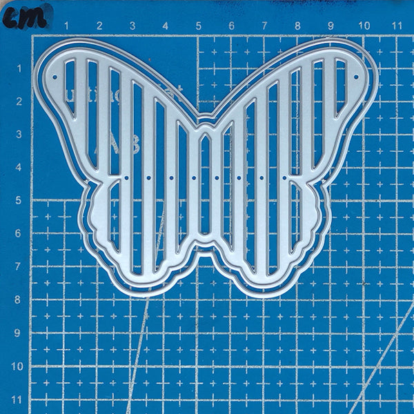 Metal butterfly-shaped cutting die on a blue grid background