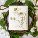 Card with floral designs and 'Hello' text on a wreath with green leaves and white flowers.