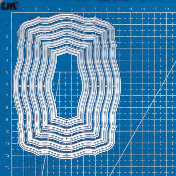 Set of layered cutting dies on a blue grid background