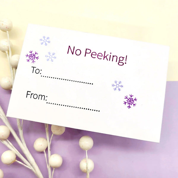 Greeting card with 'No Peeking!' text on a decorative background with snowflakes.
