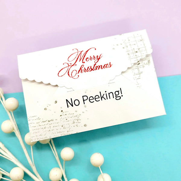 White envelope with 'Merry Christmas No Peeking!' text on a purple and blue gradient background.