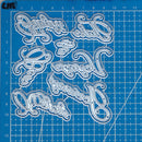 Decorative metal letters on a blue cutting mat with grid lines