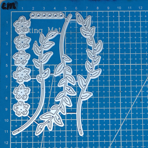 Metal die cutters with floral and leaf designs on a blue cutting mat.