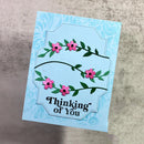 Greeting card with floral design and 'Thinking of You' text on a textured surface