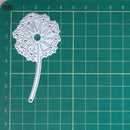 Decorative metal die on a green cutting mat with grid lines