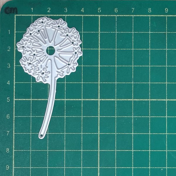 Decorative metal die on a green cutting mat with grid lines