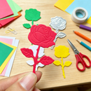 Colorful paper flower cutouts on a wooden table with scissors and tape.