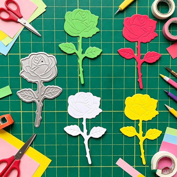 Colorful rose-shaped cutouts on a green cutting mat with craft supplies.