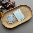 Decorative metal cutouts on a wooden tray with flowers in the background