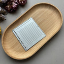 Wooden tray with a metal notebook-shaped object on a gray surface