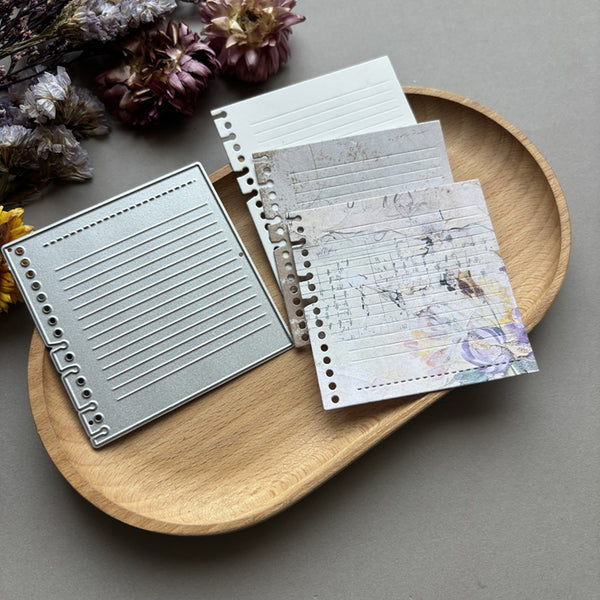 Notebook with different designs on a wooden tray with dried flowers.