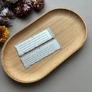 Wooden tray with two metal die-cutting templates on a gray surface with flowers.