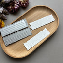 Wooden tray with metal dies and paper strips on a gray background