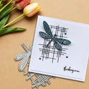 Card with dragonfly design and 'thinking of you' message, surrounded by tulips and metal dragonfly stamps on a beige background.