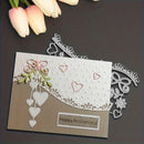 Handmade card with decorative elements and 'Happy Anniversary!' message, accompanied by tulips on a dark surface.