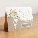 Greeting card with decorative hearts and 'Happy Anniversary!' text on a wooden surface.