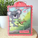 Birthday card with a koala design on a wooden surface with a plant in the background