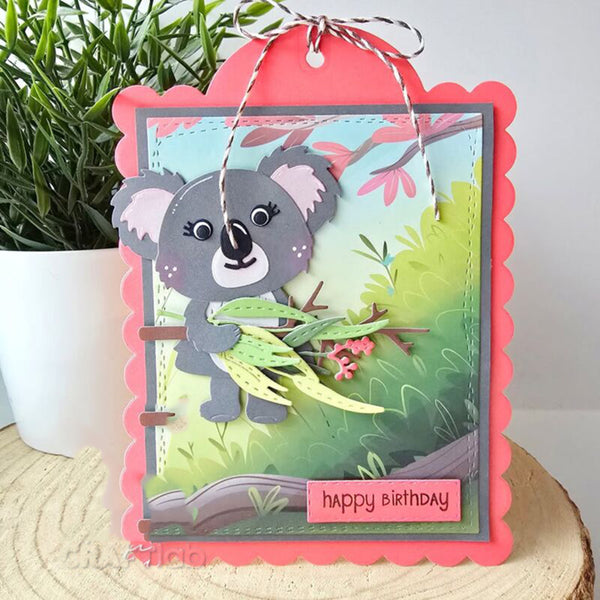 Birthday card with a koala design on a wooden surface with a plant in the background