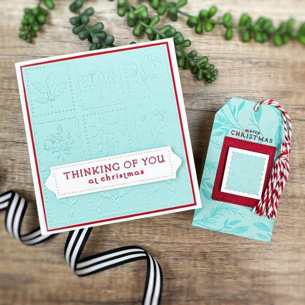 Christmas card with 'Thinking of You at Christmas' text and matching gift tag on a wooden surface.