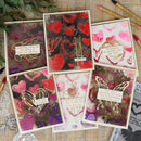 Set of handmade cards with heart designs and text on a textured surface.