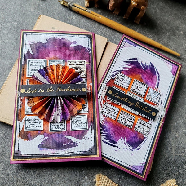 Two artistic greeting cards with decorative elements on a textured surface.