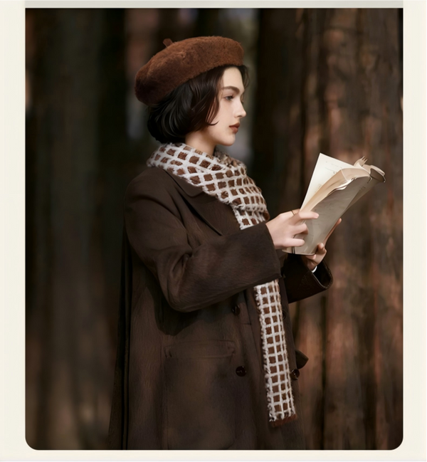 Woman in a brown coat and beret reading a book in a forest setting