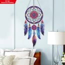 Colorful dreamcatcher hanging on a light blue wall above a bed.