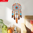 Decorative dreamcatcher with feathers hanging on a wall above a couch.