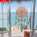 Colorful dreamcatcher diamond painting on a window with a beach view