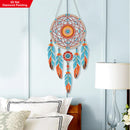 Colorful dreamcatcher hanging on a light blue wall above a bed.