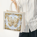Tote bag with decorative butterfly design held by a person wearing a striped shirt.