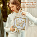Woman holding a pearl-decorated canvas bag with a butterfly design.