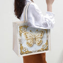 Tote bag with a decorative butterfly design held by a person wearing a white shirt.
