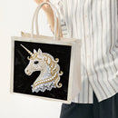 Tote bag with a decorative unicorn design held by a person wearing a striped shirt.