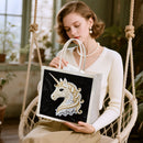Woman holding a tote bag with a unicorn design in an indoor setting