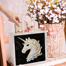 Hand holding a gift bag with a unicorn design, next to a basket of flowers.