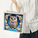 Tote bag with a decorative owl design held by a person wearing a striped shirt.