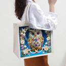 Tote bag with a decorative owl design held by a person
