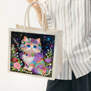 Tote bag with a colorful cat design held by a person wearing a striped shirt.