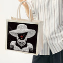 Tote bag with a decorative design of a woman wearing jewelry held by a person.