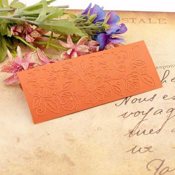 Decorative orange bookmark with floral pattern on a textured surface with flowers