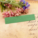 Green embossed bookmark on a vintage letter with flowers
