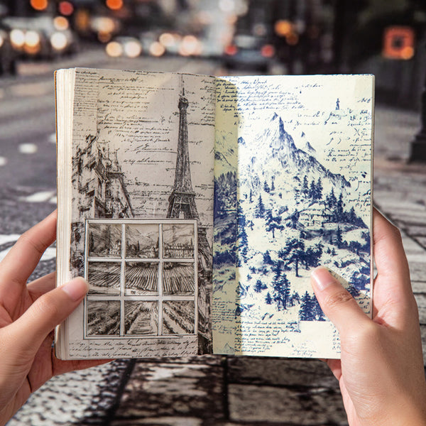 Open book with illustrated scenes of Eiffel Tower and mountain, held against a blurred city street background.
