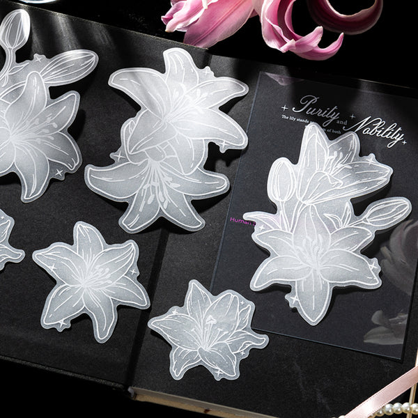 Clear floral stickers on a black book with pink flowers in the background