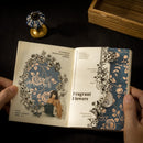 Open book with floral illustrations held by hands on a dark surface