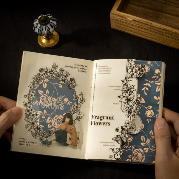 Open book with floral illustrations held by hands on a dark surface