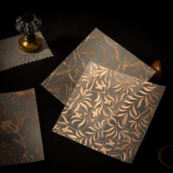 Three floral-patterned notebooks on a dark surface with a decorative object.